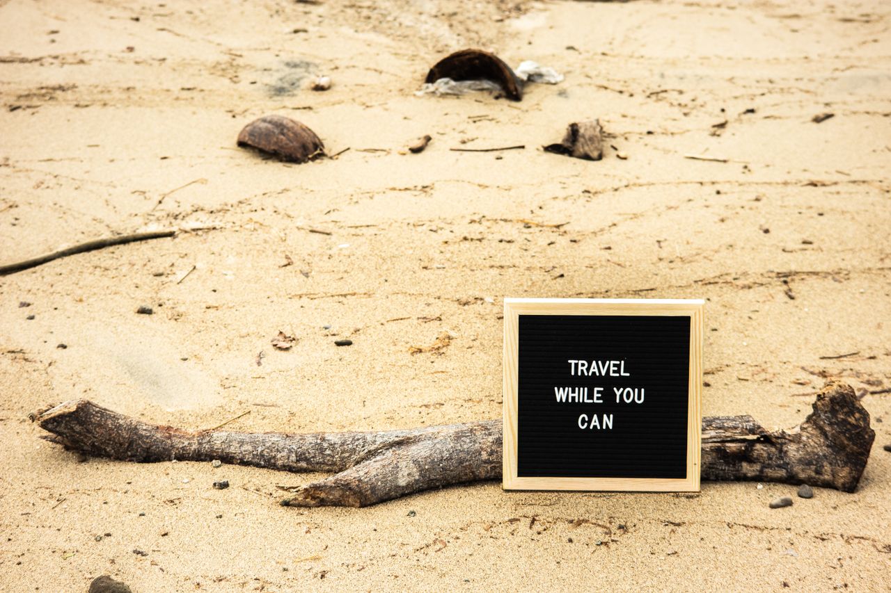 Motivational sign on sandy beach prompts travelers to seize the moment. Perfect for travel inspiration.