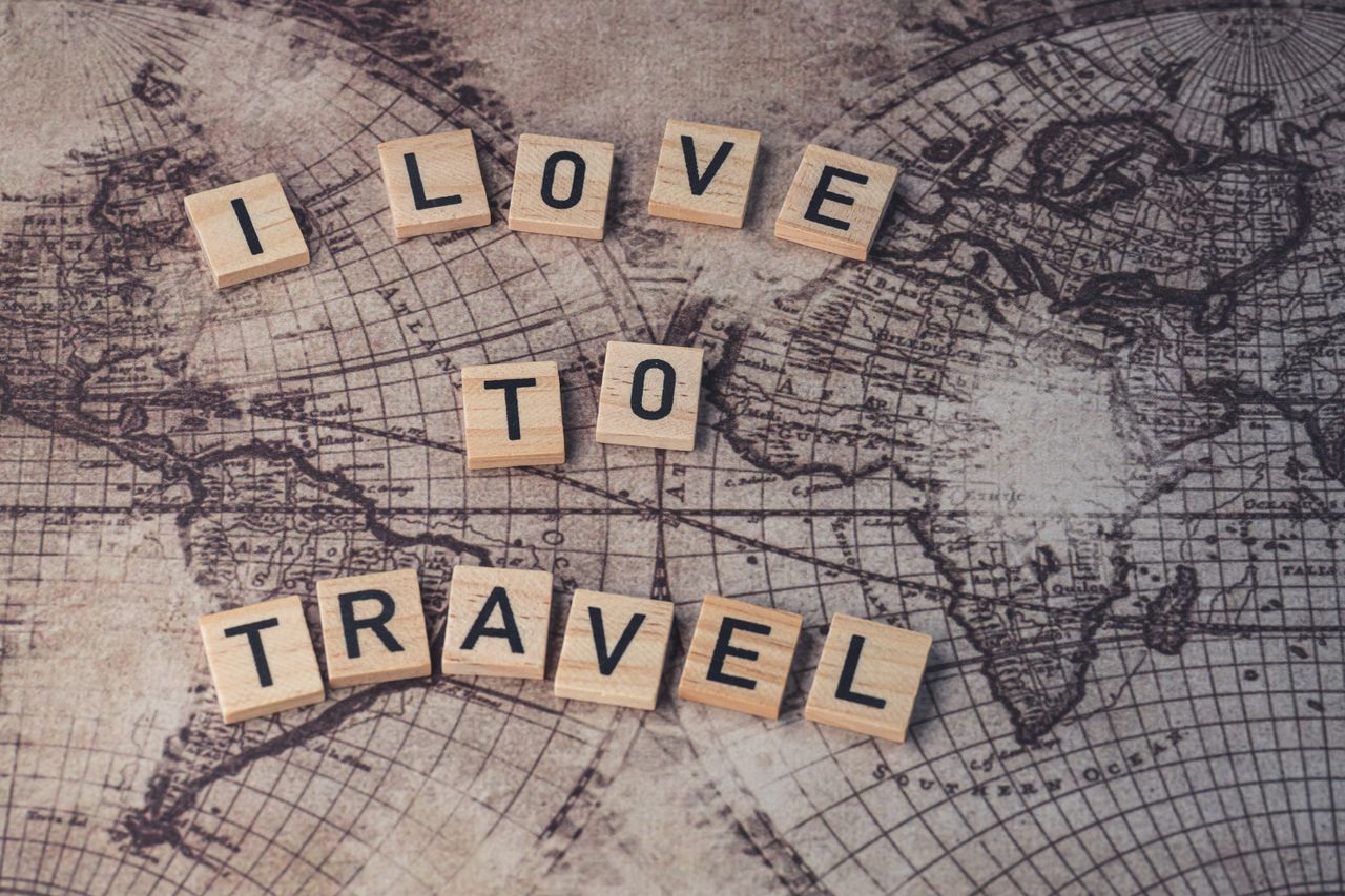 Wood scrabble tiles spelling I Love to Travel on a vintage map.